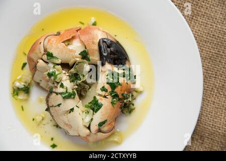 Zwei gekochte, geknackte Krabbenkrallen aus einer braunen Krabbe, Cancer Pagurus, die mit Butter, Knoblauch und Petersilie serviert wurden. Dorset England GB Stockfoto