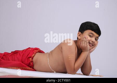 Junge indische Jungen in ethnischen tragen Verlegung oder genießen Freizeit auf weißem Hintergrund. Stockfoto