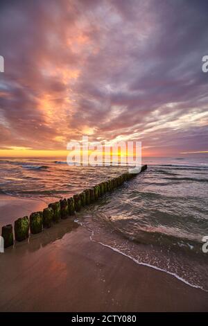 Landschaftlich schöner Sonnenuntergang über der Ostsee mit einem alten hölzernen Wellenbrecher am Strand. Stockfoto