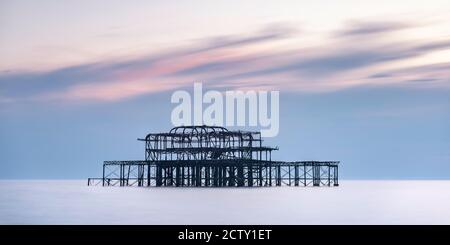 Langzeitbelichtung eines Sonnenuntergangs hinter dem alten ruinierten West Pier in Brighton, East Sussex, England Stockfoto