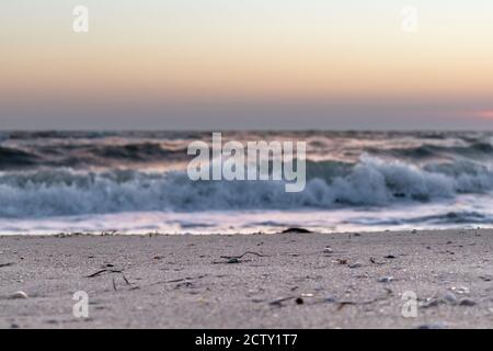 Am Meer Sandstrand in der Nähe mit Sonnenuntergang Himmel und stürmisch Weiße glänzende Wellen in Pastellfarben Stockfoto