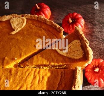 Nahaufnahme von Kürbiskuchen mit kleinen dekorativen künstlichen Kürbissen. Herbst Vibes mit traditionellen glutenfreien Kuchen. Stockfoto