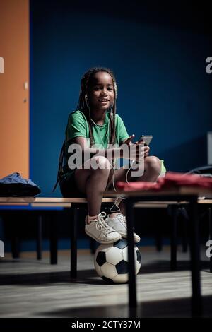 Ein kleiner Fußballspieler genießt die Musik vor dem Spiel Stockfoto