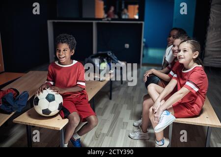 Die kleinen Fußballspieler warten auf das Spiel in einem Umkleideraum Stockfoto