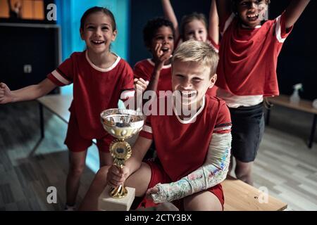 Die kleinen Fußballspieler in einem Umkleideraum sind begeistert Über den Sieg Stockfoto