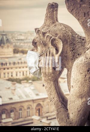 Coronavirus in Frankreich, chirurgische Maske auf dem Gargoyle von Notre Dame in Paris. Wahrzeichen wegen COVID-19 Corona Virus Pandemie geschlossen. Konzept des Reisens, qu Stockfoto