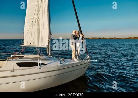 Bootsfahrt. Glückliche ältere Mann und Frau umarmen und genießen erstaunliche Aussicht, während auf der Seite des Segelboots oder Yacht Deck schwimmend in der Ruhe Stockfoto
