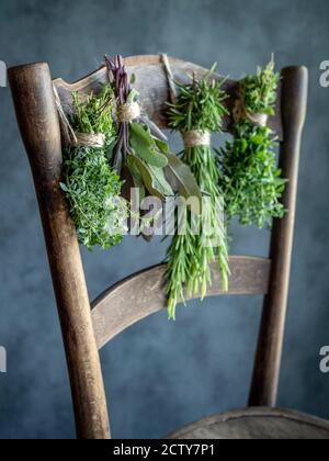 Auf einem alten Holzstuhl hängen Kräuterbünde. Thymian, Salbei, Rosmarin, Oregano. Speicherplatz kopieren. Stockfoto