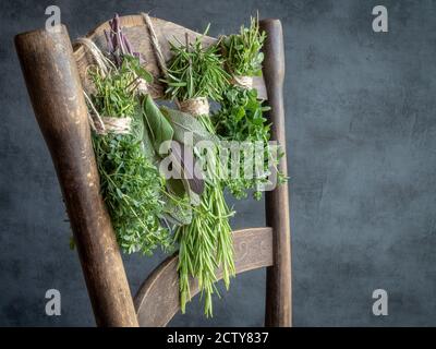 Auf einem alten Holzstuhl hängen Kräuterbünde. Thymian, Salbei, Rosmarin, Oregano. Speicherplatz kopieren. Stockfoto