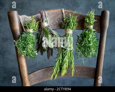 Auf einem alten Holzstuhl hängen Kräuterbünde. Thymian, Salbei, Rosmarin, Oregano. Speicherplatz kopieren. Stockfoto