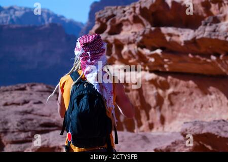 Nahaufnahme eines Westerntourists mit gelben Dreadlocks, Rucksack, Keffiyeh und ärmelloser Weste. Er genießt die wunderschöne Landschaft Stockfoto