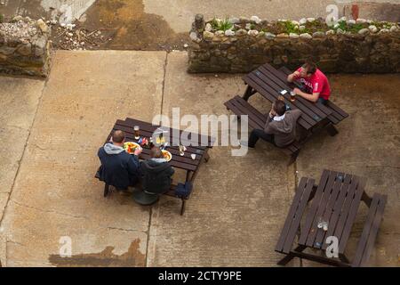 Isle of Wight, 04/25/2010: Ein Paar und ein Vater und ein Sohn werden gesehen, wie sie in einem lokalen Pub essen. Es ist im Freien sitzen an hölzernen Picknick-Tischen auf concr platziert Stockfoto