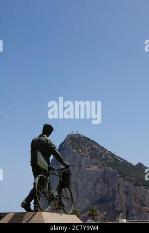 Gibraltar, UK 07/10/2010: Denkmal für spanische Arbeiter in Gibraltar: Ein Arbeiter, der aus Spanien zur Arbeit kommt, auf seinem Fahrrad mit seinem Lunchpaket, Kesselanzug Stockfoto