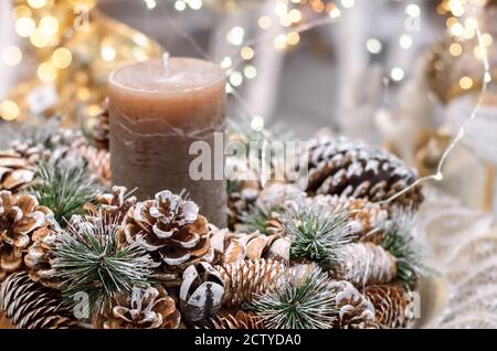 Weihnachtsdekoration mit Tannenzapfen, Tannenzweigen, Kerzen und Weihnachtslichtern. Nahaufnahme, selektiver Fokus. Stockfoto