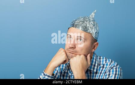 Folienhut auf Mann. Mann mit einem gelangweilten Gesicht. Schützt vor dem Lesen denken. Stockfoto