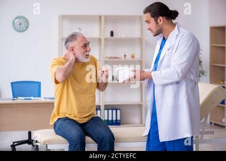 Alter Hals verletzten Mann besucht jungen Arzt Stockfoto