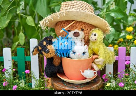 Kuscheltiere und eine große rosa Tasse in einem Blumengarten. Stockfoto