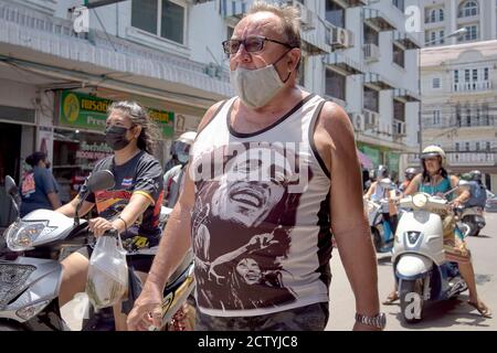 COVID-19 Gesichtsmaske. Reifer Mann trägt Gesichtsmask und Bob Marley Singlet Shirt. Thailand Straße Südostasien Stockfoto