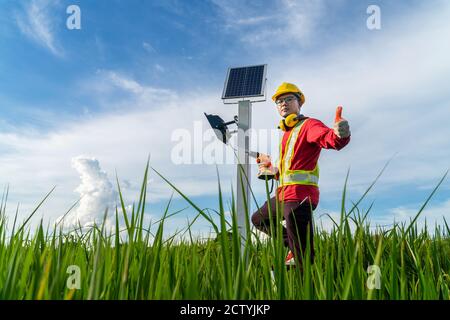 Asian Techniker installieren die Wartung der Sonnenkollektoren geben Vertrauen in Qualität, Außenbeleuchtung Stange mit kleinen Solarpanel Strom durch thems Stockfoto