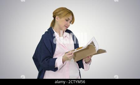 Schwangere blonde Frau Lesemagazin auf Gradienten Hintergrund. Stockfoto