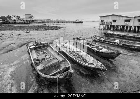 Hafenblick von einem der Clan-Anlegestellen im historischen George Town, Penang, Malaysia - Chew Jetty. Holzboote liegen bei Ebbe in bewölktem regnerischem Wetter Stockfoto