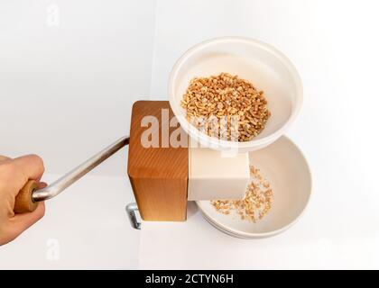 Kornwalze oder Korntaufler. Verwendet, um natürliche Haferflocken zu machen. Hooper wird mit ganzen Körnern gefüllt: Hafer, Gerste und Farro. Gesunde Ernährung. Stockfoto