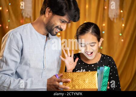 Aufgeregt kleine Schwester bekam Geschenk von ihrer Mühe während Raksha Bandhan, Bhai Dooj oder Bhaubeej indischen religiösen Festzeremonie Stockfoto