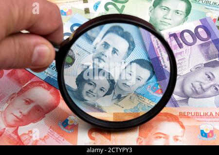 Philippinischer Peso in einer Lupe ein geschäftlicher Hintergrund Stockfoto