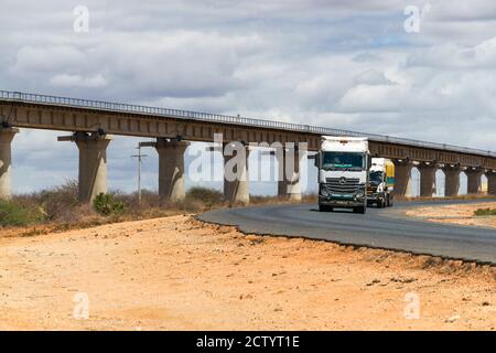 Ein großer LKW, der entlang der Autobahn Mombasa fuhr und Waren mit der SGR-Eisenbahn im Hintergrund, Kenia, transporte Stockfoto