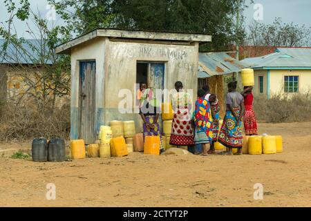 Eine Gruppe von afrikanischen Frauen und Kinder Schlange wasser Behälter an einem Wasser Kiosk im ländlichen Kenia zu füllen Stockfoto