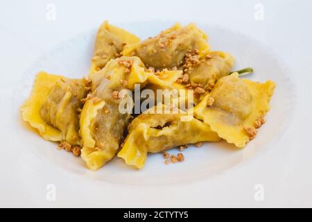 Tortelli di Zucca alla Mantovana aus Mantua, Lombardei, Italien auf einem weißen Teller mit Salbei Butter und Amaretti Krümel Stockfoto