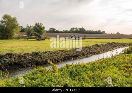 Auf einer Wiese gibt es Traktoren und Bagger zu graben Ein Wassergraben Stockfoto