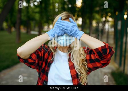 Frau in Maske und Handschuhe bedeckt Gesicht, Quarantäne Stockfoto