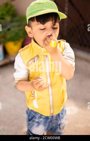 Schneiden Sie kleinen Jungen essen Lollipop Süßigkeiten und Spaß im Freien zu Tageszeiten. Stockfoto