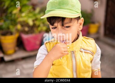 Schneiden Sie kleinen Jungen essen Lollipop Süßigkeiten und Spaß im Freien zu Tageszeiten. Stockfoto