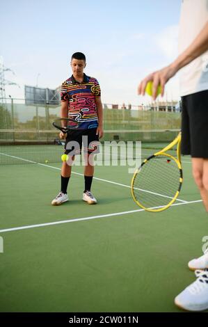 Männliche Tennisspieler mit Schlägern treffen die Bälle Stockfoto