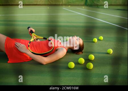 Müde weibliche Tennisspielerin liegt auf dem Platz Stockfoto