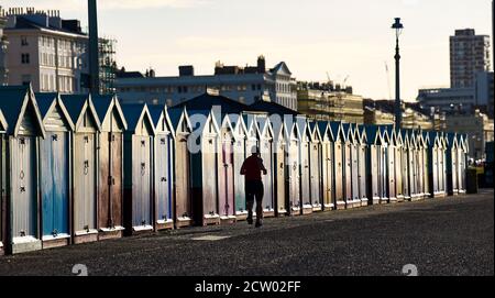 Brighton, Großbritannien. September 2020. Ein Läufer passiert bunte Strandhütten entlang der Küste von Hove an einem hellen und sonnigen, aber kalten Morgen entlang der Südküste. : Credit: Simon Dack/Alamy Live News Stockfoto