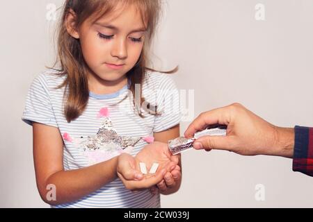 Der Mensch gibt einem Kind Minze Kaugummi. Nach dem Essen die Zähne mit Kaugummi reinigen. Frischer Atem. Mädchen nimmt Stock von Gummi. Schlechte Gewohnheit, schädlich Stockfoto