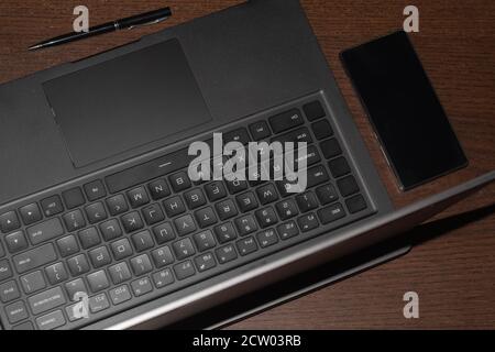 Laptop-Computer, Handy und Stift, auf einem Holztisch Stockfoto