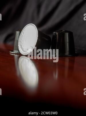 Detail der italienischen Espresso Kaffeekapseln mit Spiegelung im Holz. Selektiver Fokus Stockfoto
