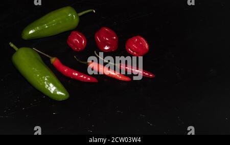 Schieferteller verschiedener Arten von roten und grünen Paprika wie Serenade, Chili, jalapeños, Chiles, Naga, Habanero, Scorpion Stockfoto