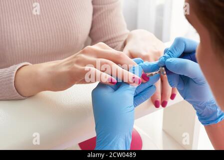 Maniküre Master verwendet eine elektrische Nagelmaschine, um Nagellack Hände im Nagelstudio zu entfernen Stockfoto