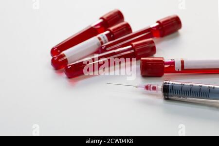 Injektionsspritze mit Blutprobenfläschchen von Patienten und Impfstoff Flaschen auf weißem Hintergrund Stockfoto