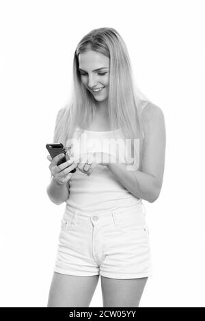 Studio shot Junger happy teenage Mädchen lächelnd, während mit Handy Stockfoto