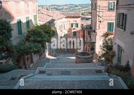 Eine Treppe in einem mittelalterlichen italienischen Dorf mit einem alten Ziegelbrunnen (Corinaldo, Marken, Italien, Europa) Stockfoto