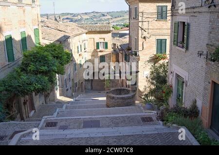 Eine Treppe in einem mittelalterlichen italienischen Dorf mit einem alten Ziegelbrunnen (Corinaldo, Marken, Italien, Europa) Stockfoto