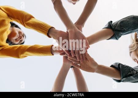 Low-Angle-Aufnahme einer Gruppe von Frauen, die einen Stapel Hände in einem Huddle bilden, das Teamwork, Freundschaft und Einheit symbolisiert. Stockfoto