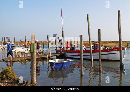 Passagiere, die von einer Robbenfahrt aussteigen und ein Boot in Morston Creek in North Norfolk in Morston, Norfolk, England, Großbritannien, besichtigen. Stockfoto