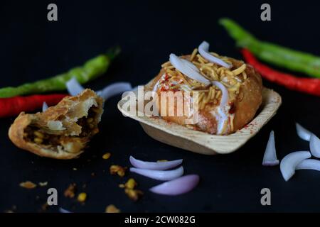 Indischer gebratener Chat Kachori mit Quark und sev und Zwiebeln auf schwarzem Hintergrund mit grünen und roten Chilis gekrönt. Stockfoto